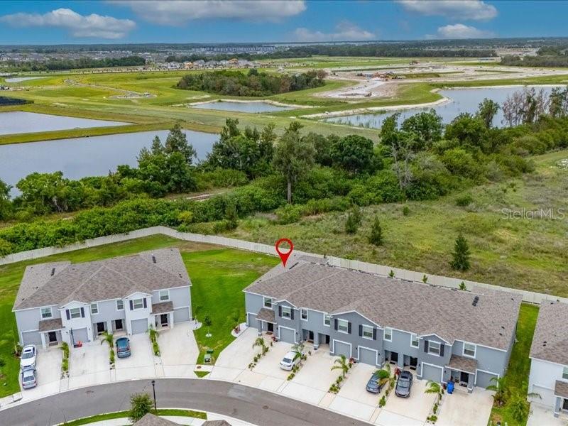 An aerial view shows two rows of multi-story townhomes with driveways and a nearby pond — 416 MANGROVE SHADE CIRCLE, APOLLO BEACH, FL