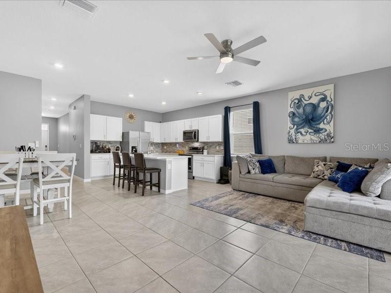 An open-concept kitchen and living area with white cabinets, tile flooring, and a sectional sofa — 416 MANGROVE SHADE CIRCLE, APOLLO BEACH, FL