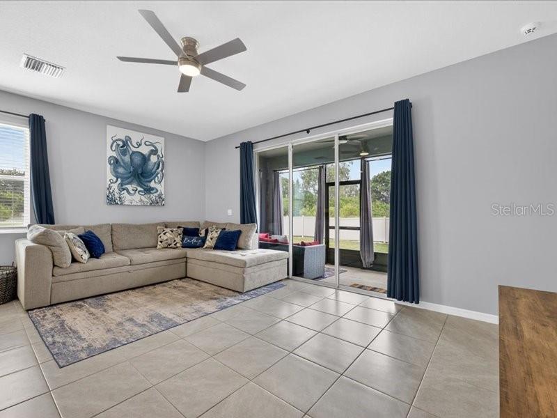 A living room features a sectional sofa, tile flooring, a ceiling fan, and sliding glass doors — 416 MANGROVE SHADE CIRCLE, APOLLO BEACH, FL