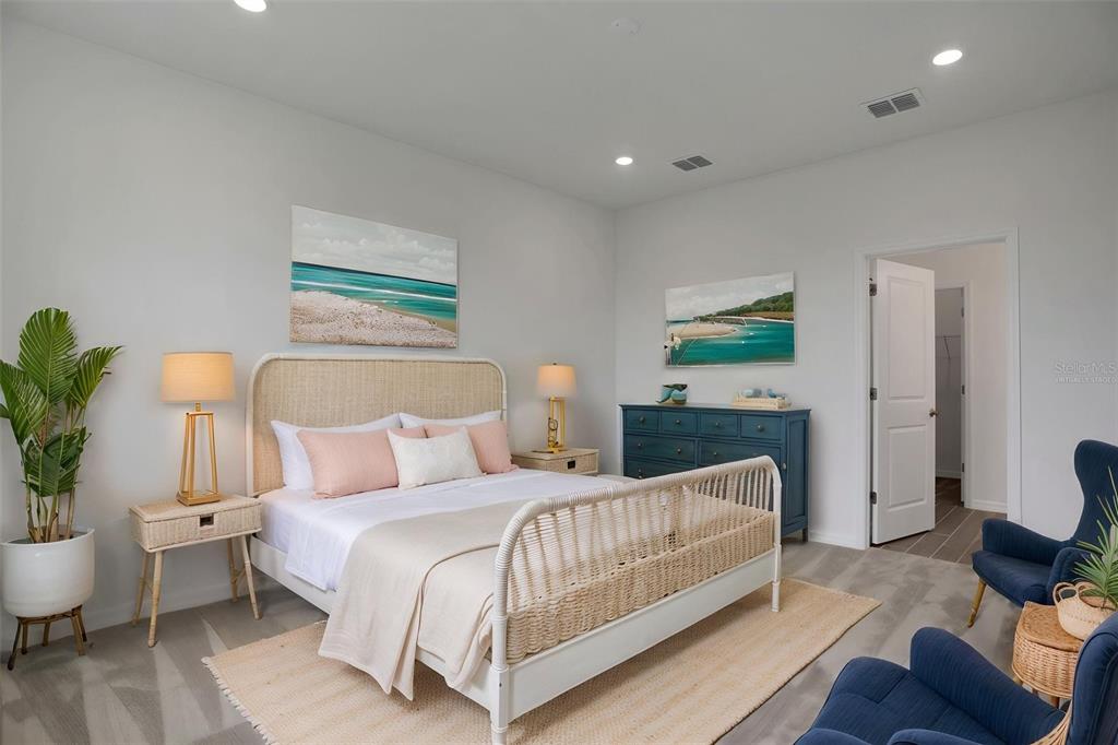 A bedroom features a wicker bed, two blue armchairs, a blue dresser, and coastal artwork — 8090 SUNNY POINT TRAIL, PARRISH, FL