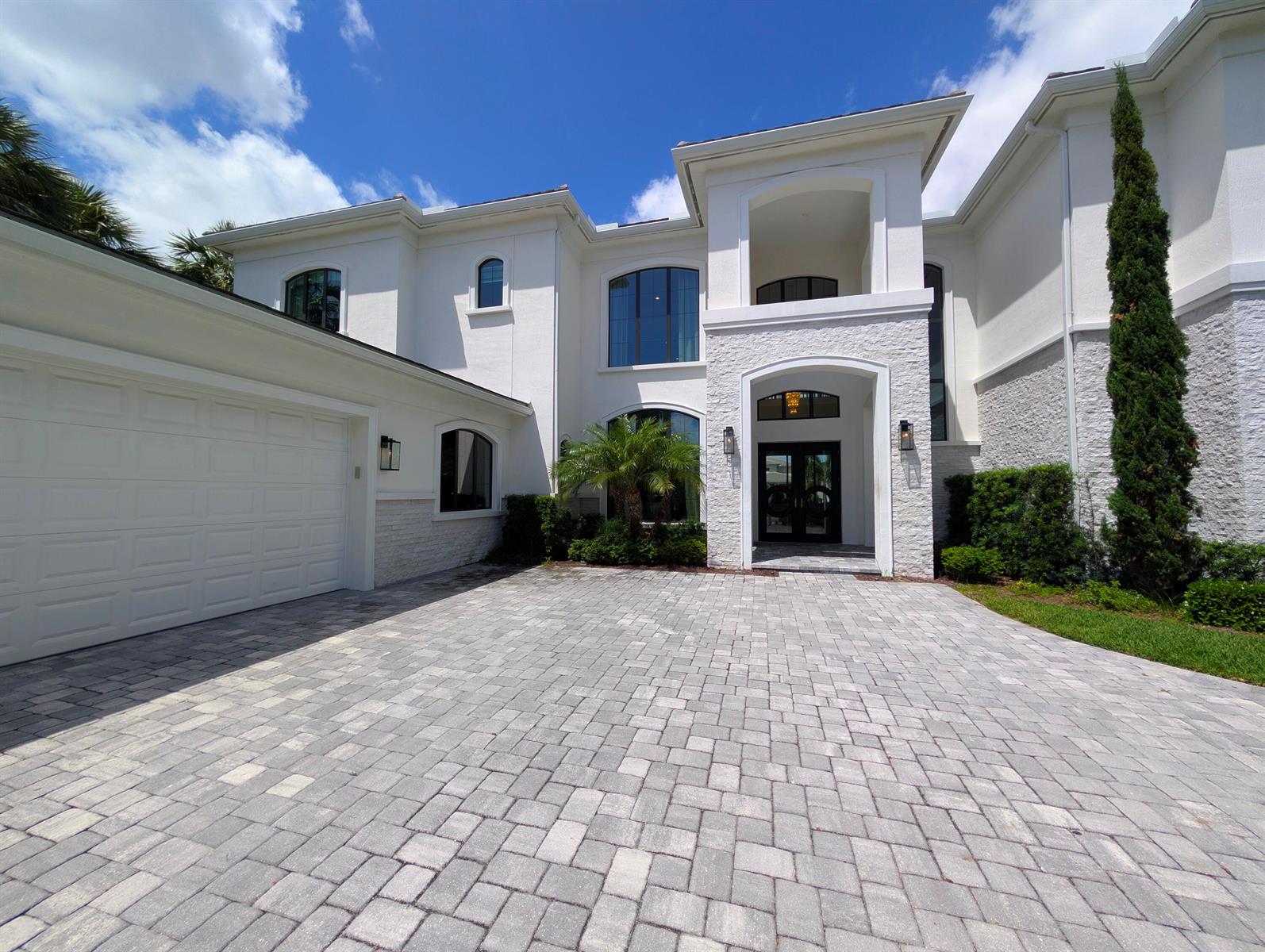 A two-story white stucco house with a stone facade, arched windows, and a paved driveway — 7080 NW 26th Way, Boca Raton FL 33496, BOCA RATON, FL