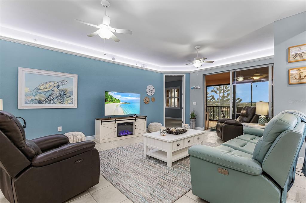 A living room features light blue walls, two ceiling fans, and a white media console — 24399 BALTIC AVENUE UNIT 202, PUNTA GORDA, FL