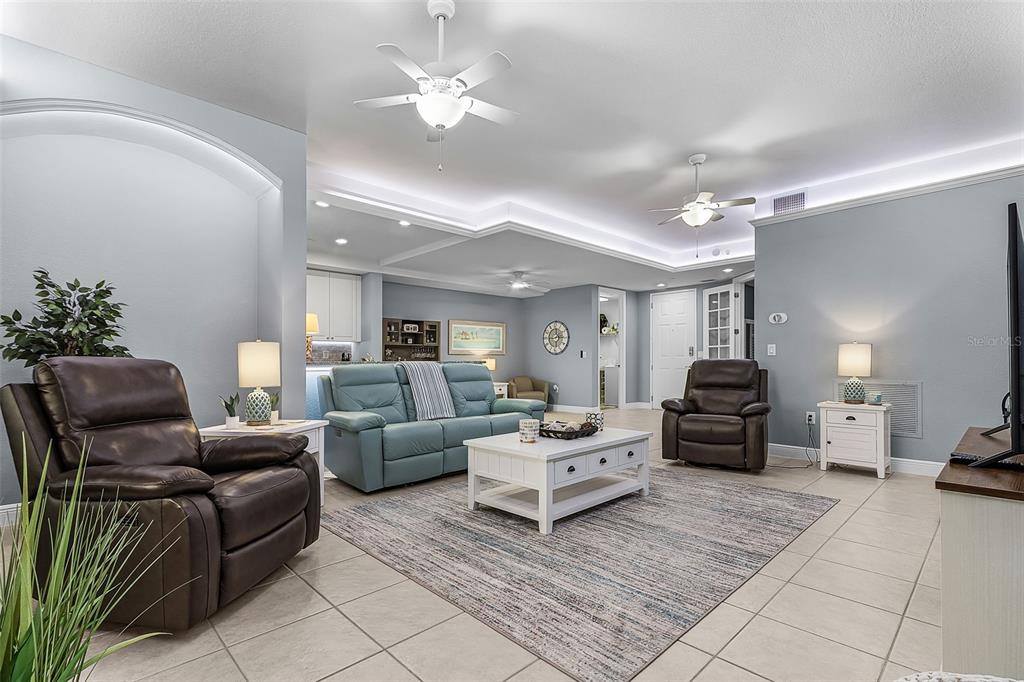 A living room features light blue walls, tile flooring, a tray ceiling, and leather furniture — 24399 BALTIC AVENUE UNIT 202, PUNTA GORDA, FL