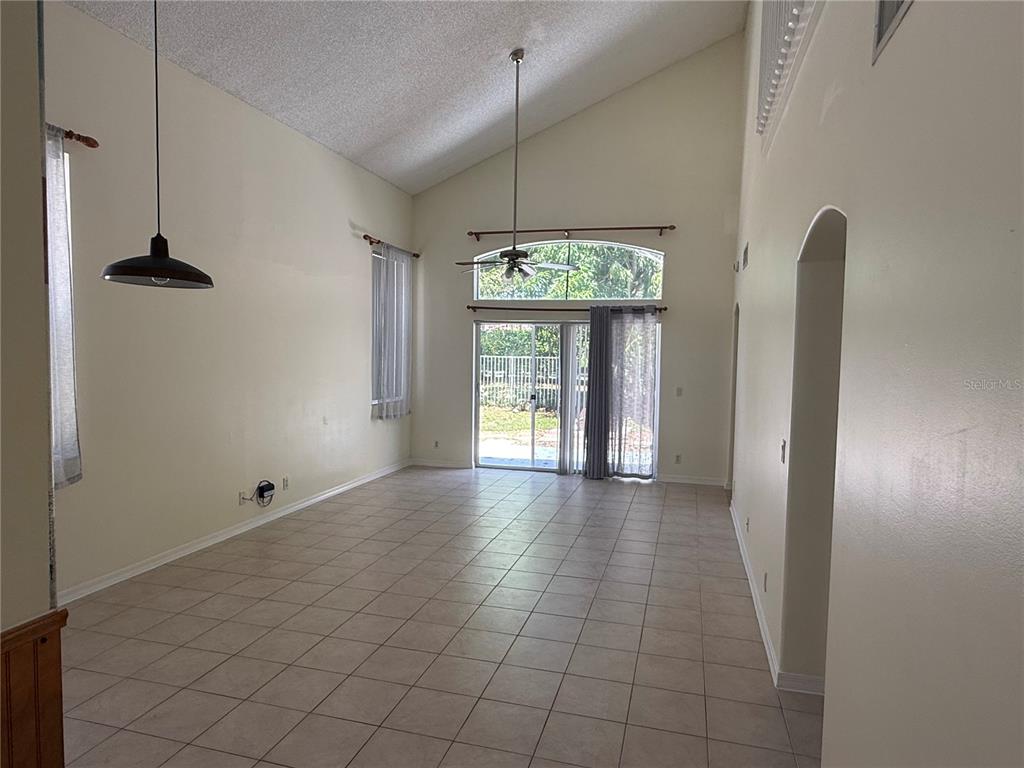 A spacious living room features vaulted ceilings, tile flooring, and a sliding glass door — 6711 GREEN ISLAND CIRCLE, LAKE WORTH, FL