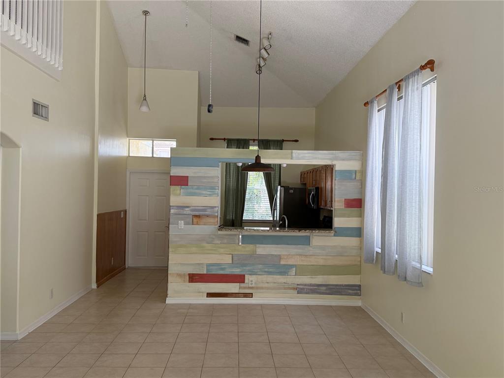 A tiled room features a multi-colored wood-paneled partition wall separating the kitchen from living space — 6711 GREEN ISLAND CIRCLE, LAKE WORTH, FL