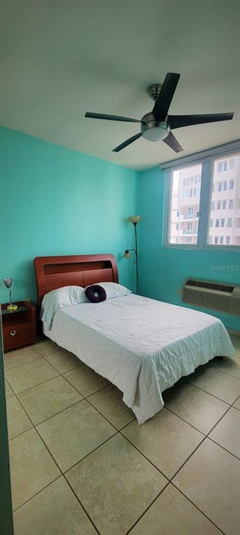 A bedroom with turquoise walls, a wooden bed frame, tile flooring, and a ceiling fan — 1400 JOSE DE DIEGO AVE COND PALACIOS DEL ESCORIAL UNIT 9-51, CAROLINA, PR