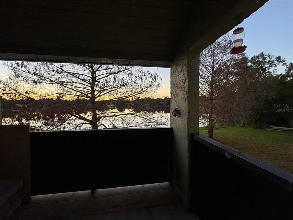 A covered balcony overlooks a lake at sunset with a lawn to the right — 912 LAKE DESTINY ROAD UNIT G, ALTAMONTE SPRINGS, FL