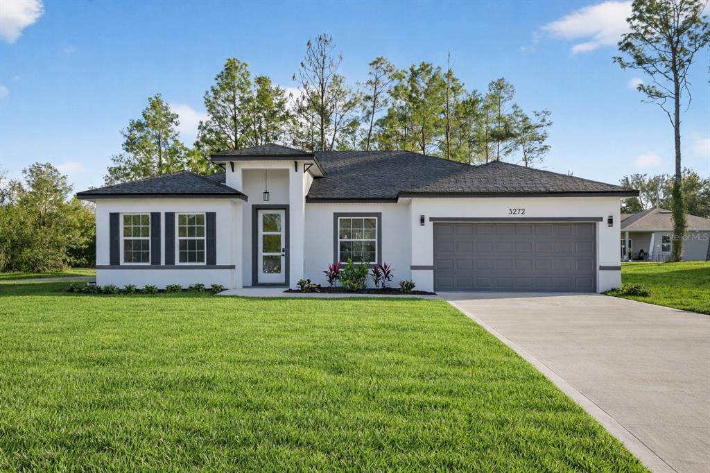 A single-story house with a white stucco exterior, dark gray shutters, and a two-car garage — 3272 W FAIRBANK DRIVE, CITRUS SPRINGS, FL