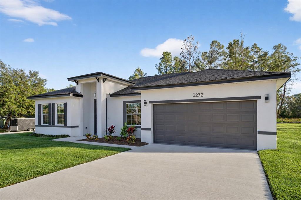 A modern single-story house with a white stucco exterior, dark trim, and a two-car garage — 3272 W FAIRBANK DRIVE, CITRUS SPRINGS, FL