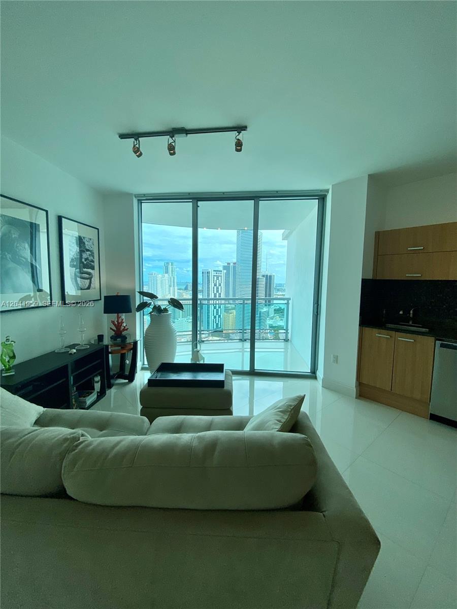 A living room features a beige sofa, track lighting, and a balcony with city views — 350 S Miami Ave # 3813, Miami FL 33130, MIAMI, FL