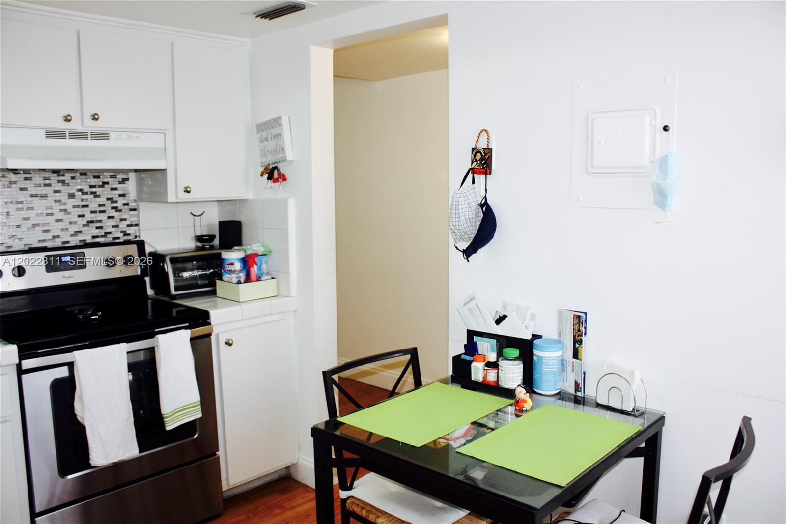 A kitchen features white cabinets, a stainless steel stove, and a small glass dining table — 18555 NE 14th Ave # 702A, Miami FL 33179, MIAMI, FL