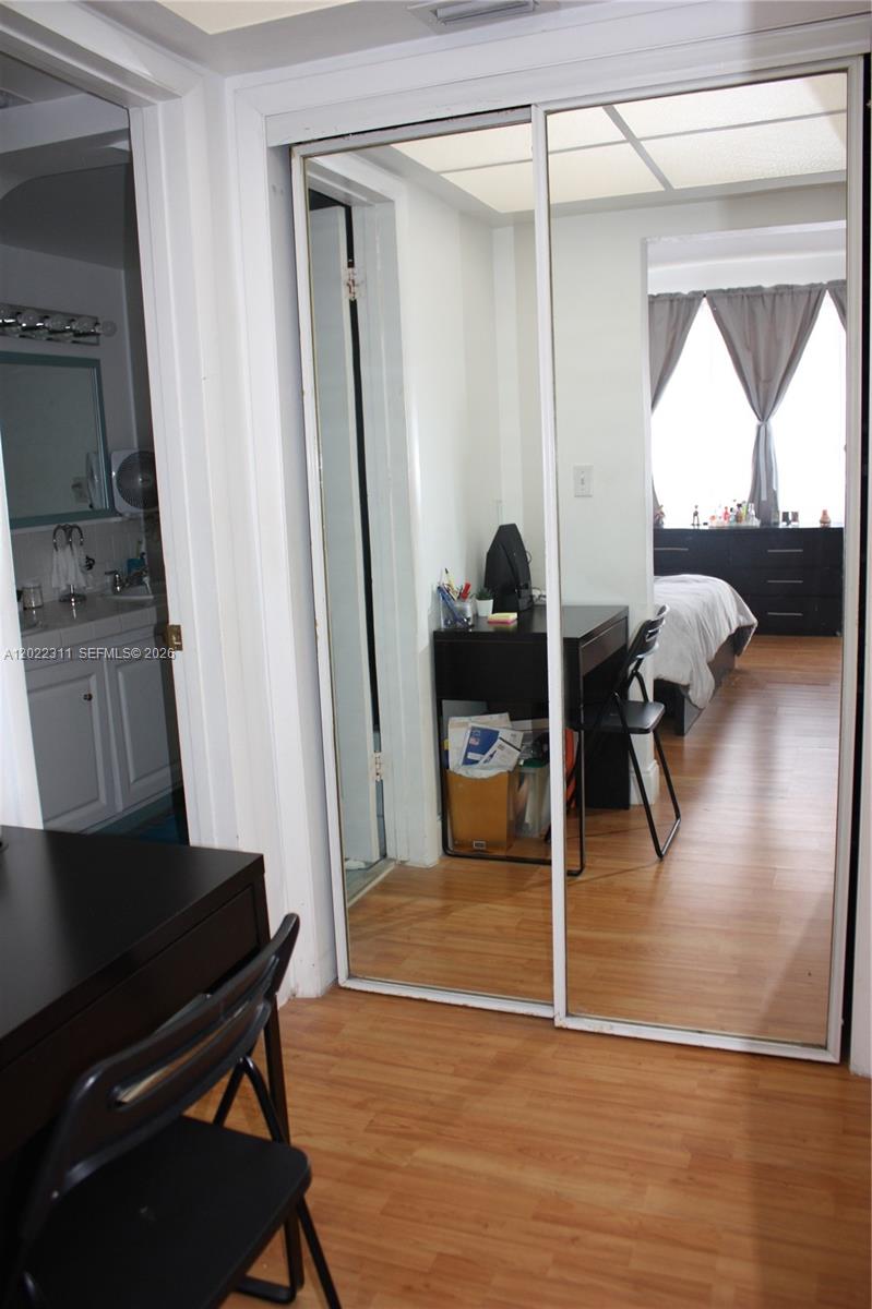 A bedroom features a mirrored closet, a desk with a chair, and an adjacent bathroom — 18555 NE 14th Ave # 702A, Miami FL 33179, MIAMI, FL