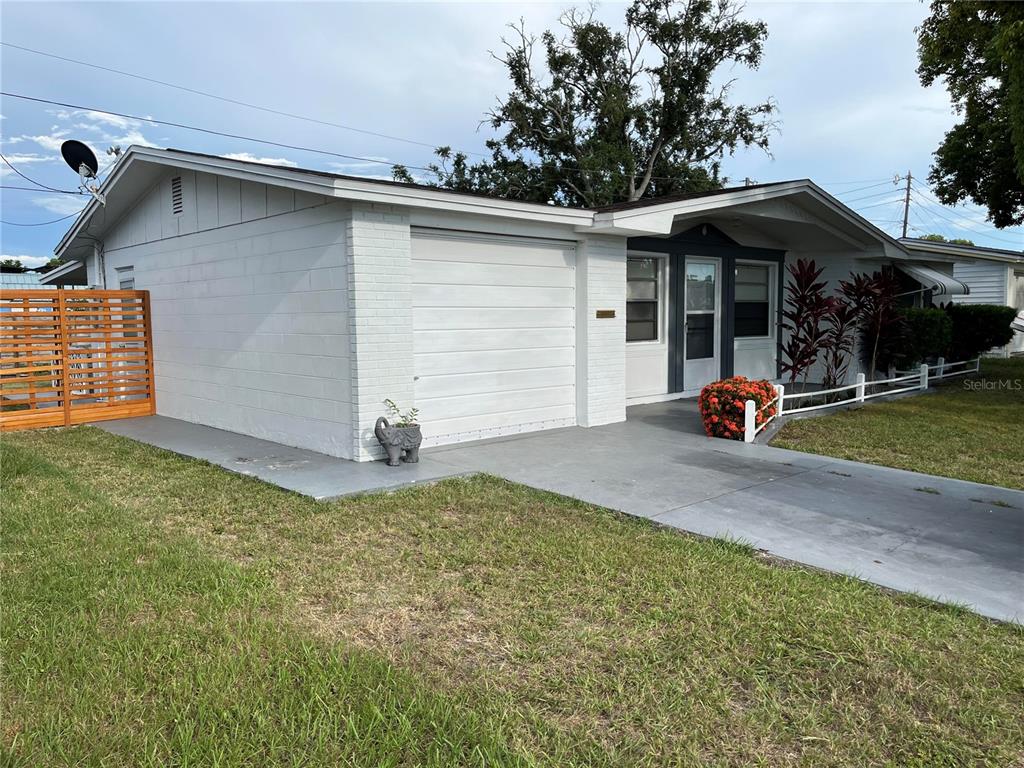 A white, single-story house with a garage, a wooden privacy fence, and a concrete driveway — 3632 PENSDALE DRIVE, NEW PORT RICHEY, FL