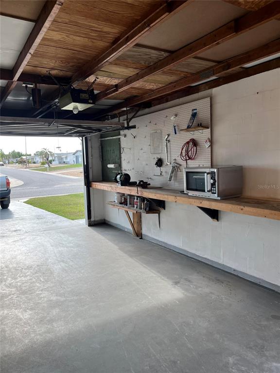 A garage features a workbench with a pegboard, a microwave, and an open ceiling — 3632 PENSDALE DRIVE, NEW PORT RICHEY, FL