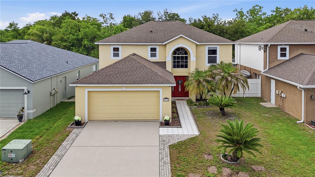 An aerial view of a two-story yellow house with a two-car garage and driveway — 24945 RAVELLO STREET, LAND O LAKES, FL