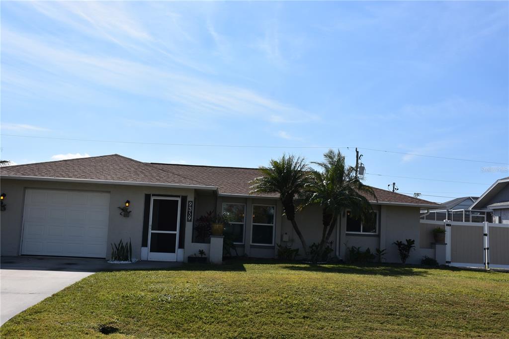 A single-story house with a beige exterior, a garage, and palm trees in the front yard — 9359 CASA GRANDE AVENUE, ENGLEWOOD, FL