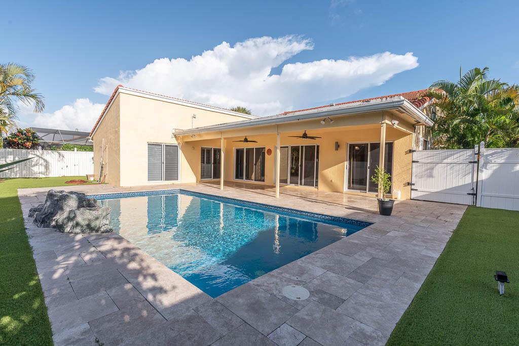 A backyard features a swimming pool with a rock feature, patio, and artificial turf lawn — 251 NW 69th Street, Boca Raton FL 33487, BOCA RATON, FL
