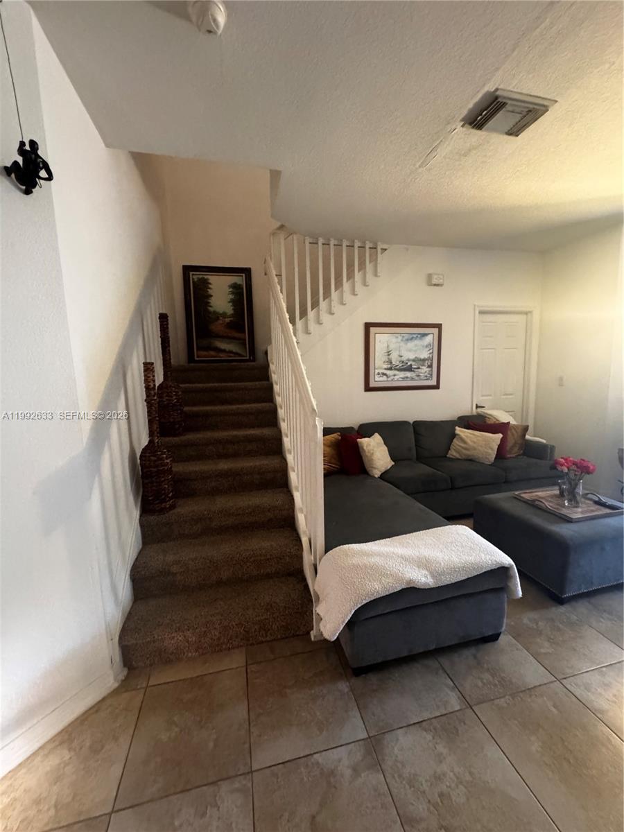A living room features a carpeted staircase, a gray sectional sofa, and tile flooring — 10723 NW 85th Ter # 38, Doral FL 33178, DORAL, FL