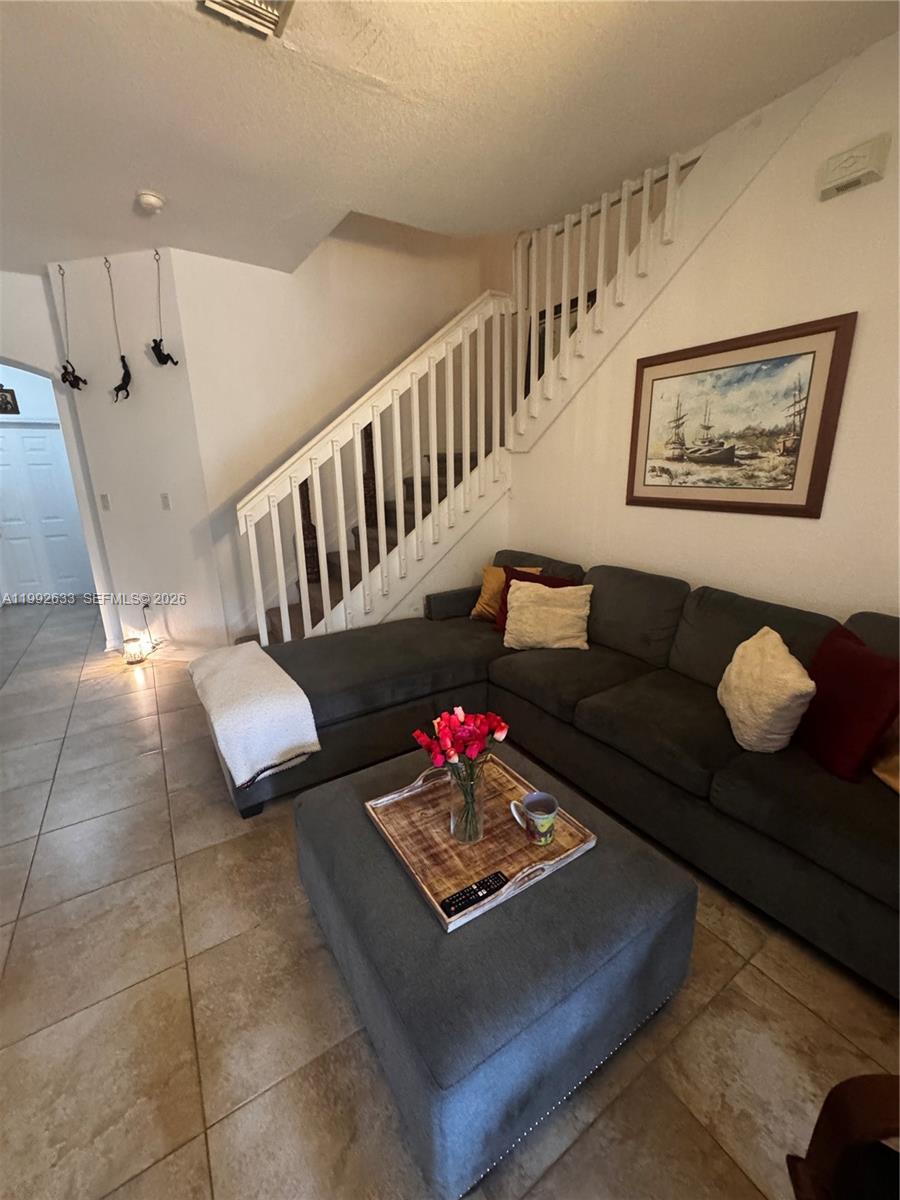 A living room features a gray sectional sofa, a matching ottoman, and a white staircase — 10723 NW 85th Ter # 38, Doral FL 33178, DORAL, FL