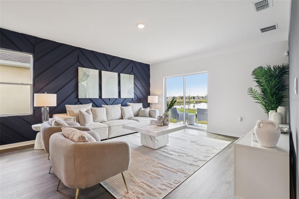 A living room features a dark blue chevron accent wall, beige sectional, and sliding glass doors — 5335 CLOUDBERRY AVENUE, LAKELAND, FL