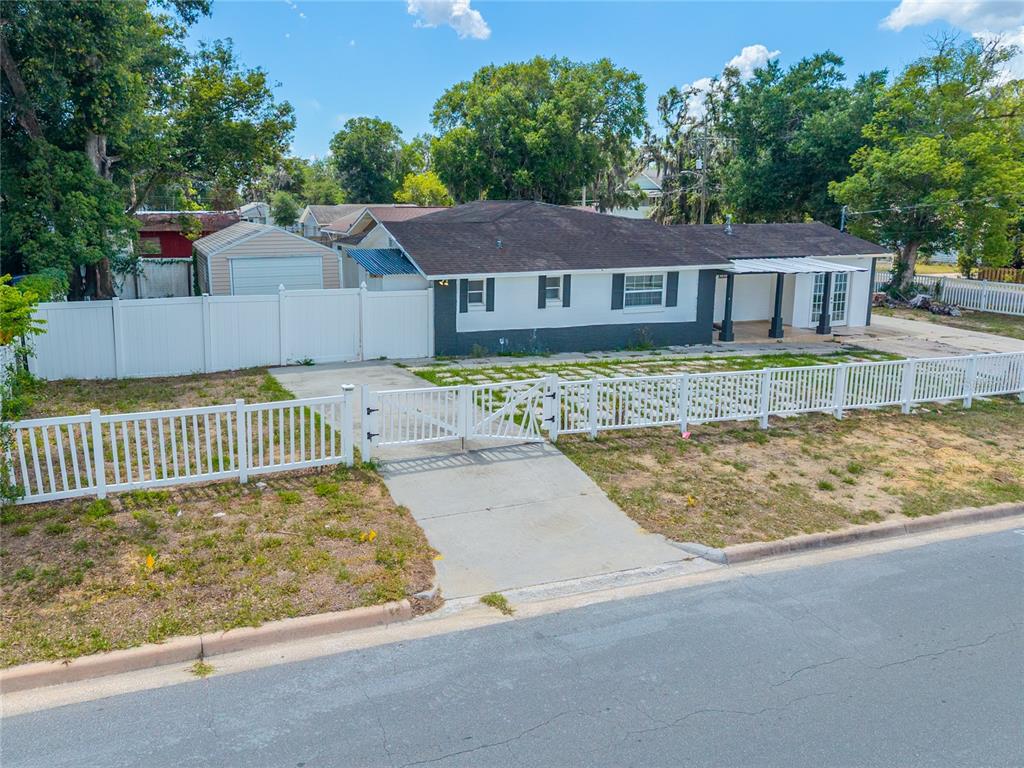 A single-story house with a white fence, a detached garage, and a paved driveway — 1230 E 1ST AVENUE, MOUNT DORA, FL