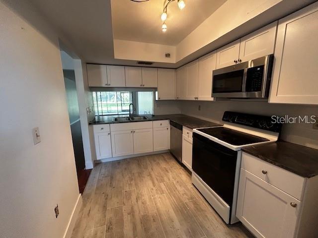 A kitchen features white cabinets, stainless steel appliances, and light wood-look tile flooring — 5647 SUMMER SIDE LANE UNIT 41A, SARASOTA, FL