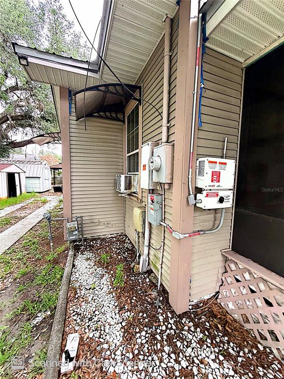 The exterior side of a house features siding, utility meters, and a small window awning — 118 W DREW STREET, PLANT CITY, FL