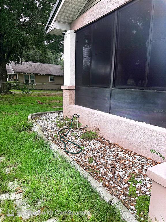 A view of a house exterior featuring a screened-in porch and a gravel garden bed — 118 W DREW STREET, PLANT CITY, FL