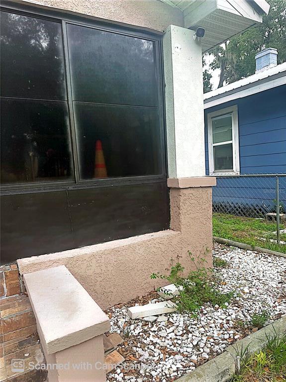 The exterior of a house features a screened-in porch, stucco walls, and a gravel yard — 118 W DREW STREET, PLANT CITY, FL