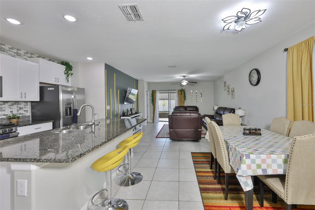 An open-concept kitchen, dining area, and living room featuring tile floors and granite countertops — 10335 SHADY PRESERVE DRIVE, RIVERVIEW, FL