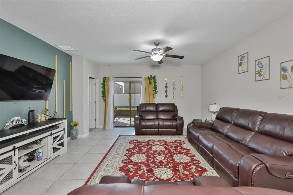 A living room features brown leather furniture, a red patterned rug, and a teal accent wall — 10335 SHADY PRESERVE DRIVE, RIVERVIEW, FL