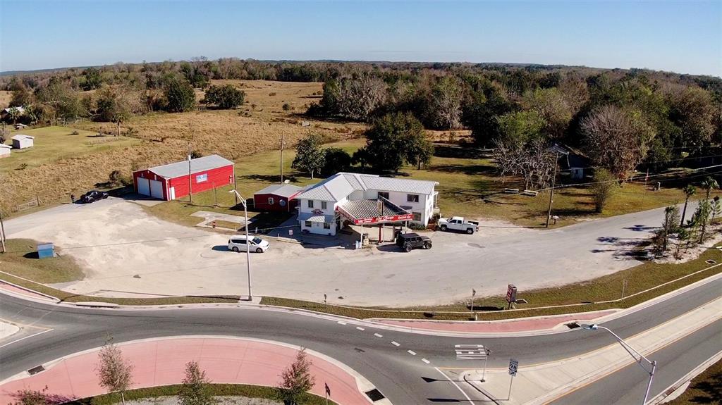An aerial view shows a commercial building with a gas canopy, a red garage, and parking — 15738 PONCE DE LEON BOULEVARD, BROOKSVILLE, FL