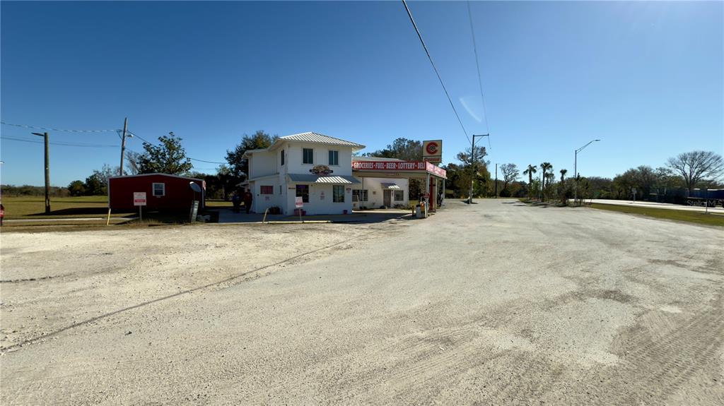 A white two-story commercial building with a gas station canopy sits on a gravel lot — 15738 PONCE DE LEON BOULEVARD, BROOKSVILLE, FL