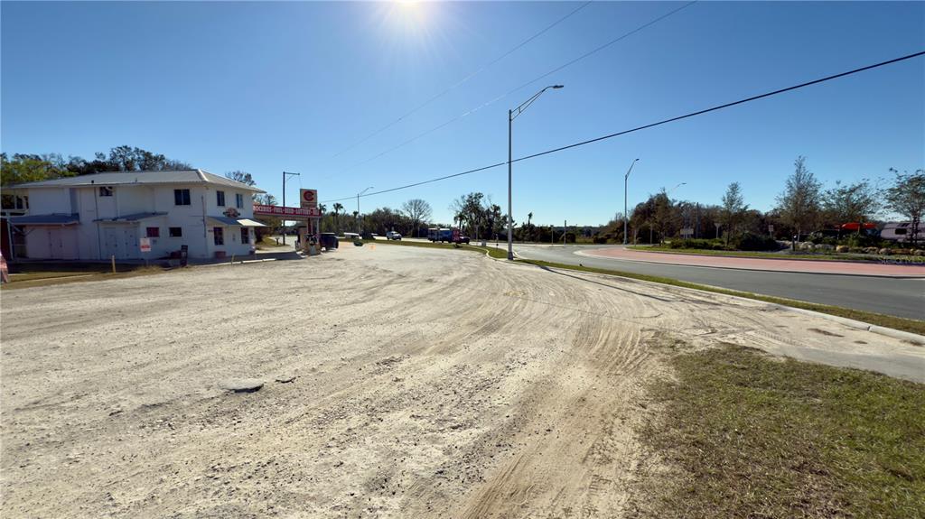 A white building sits next to a large dirt lot beside a paved road — 15738 PONCE DE LEON BOULEVARD, BROOKSVILLE, FL