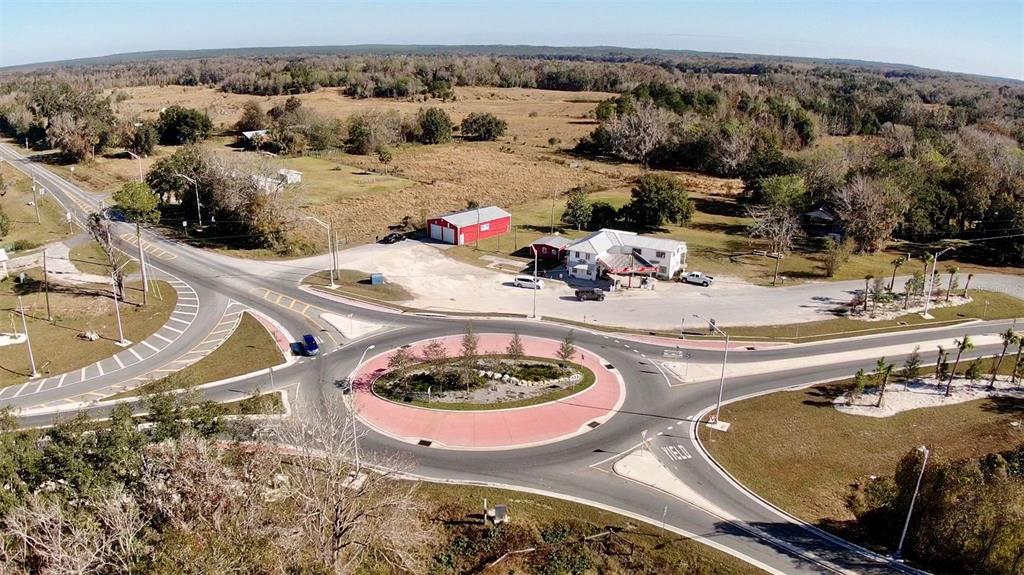 An aerial view shows a roundabout intersection next to a commercial building and a red barn — 15738 PONCE DE LEON BOULEVARD, BROOKSVILLE, FL