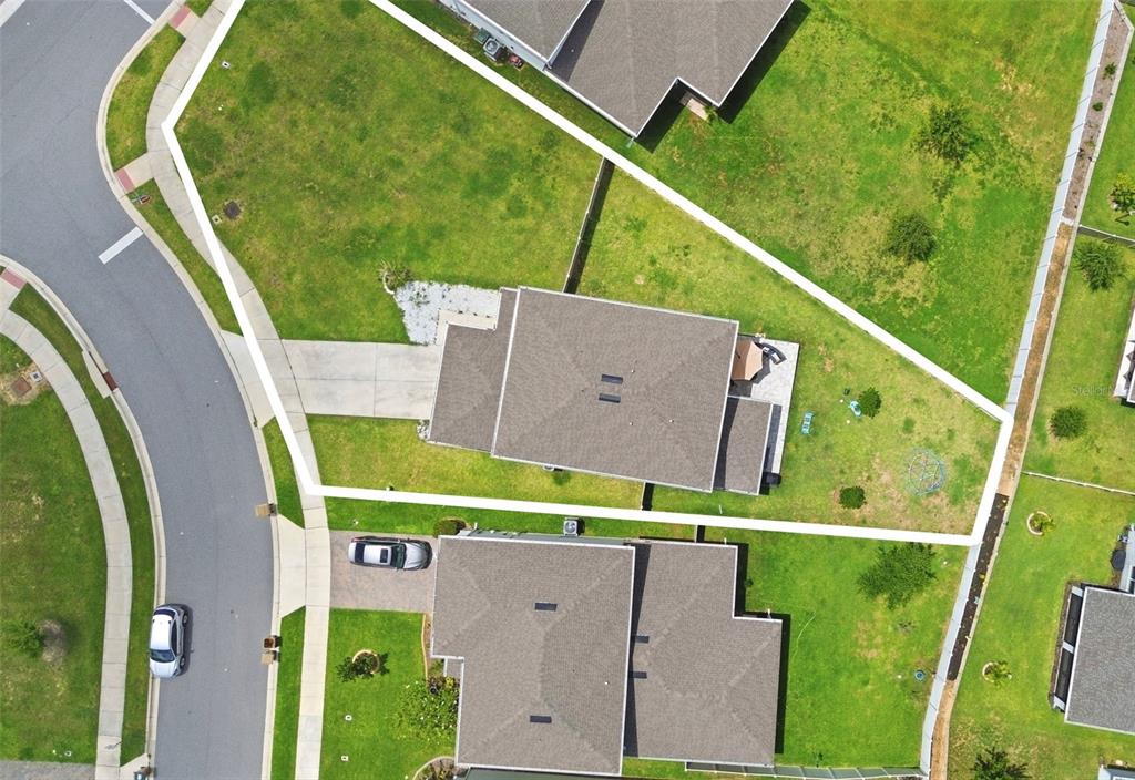 An aerial view shows a residential house with a large, fenced-in backyard — 7603 TAORMINA WAY, CLERMONT, FL