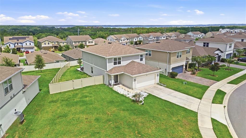 An aerial view shows a two-story suburban house with a tan exterior and fenced yard — 7603 TAORMINA WAY, CLERMONT, FL