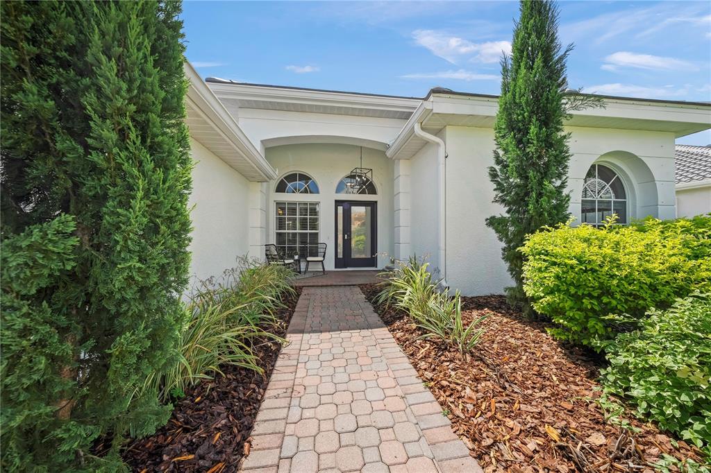 A paved walkway leads to the front entrance of a white house with arched windows — 8275 BARTON FARMS BOULEVARD, SARASOTA, FL
