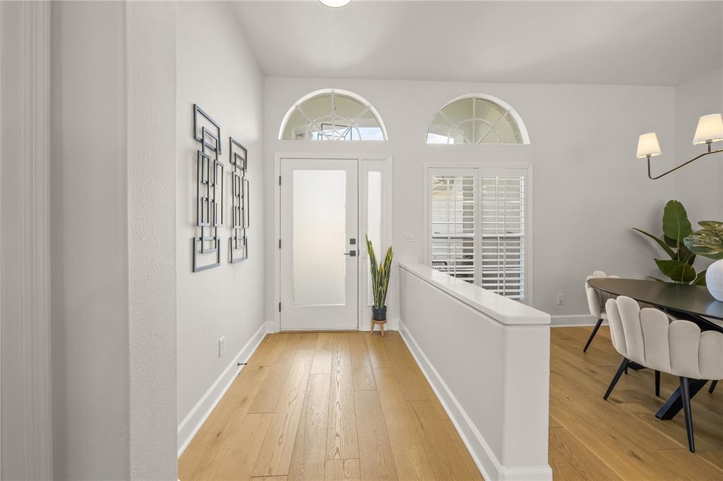 A bright entryway features light wood flooring, a white front door, and a dining area — 8275 BARTON FARMS BOULEVARD, SARASOTA, FL