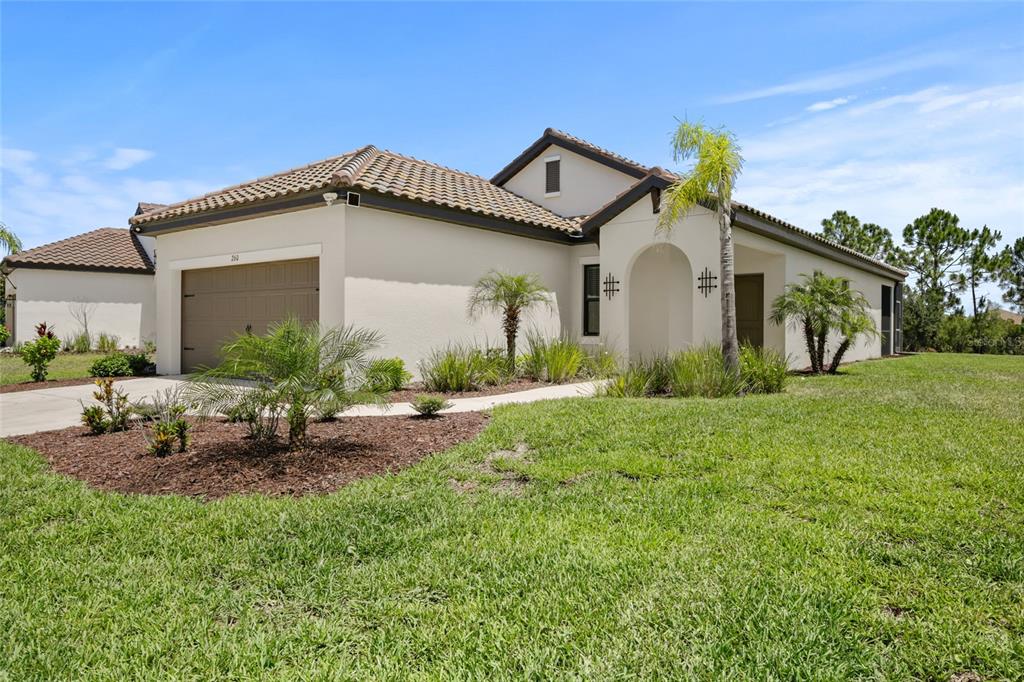 A single-story house with a tan stucco exterior, tile roof, and a two-car garage — 260 BRIENZA LOOP, NOKOMIS, FL
