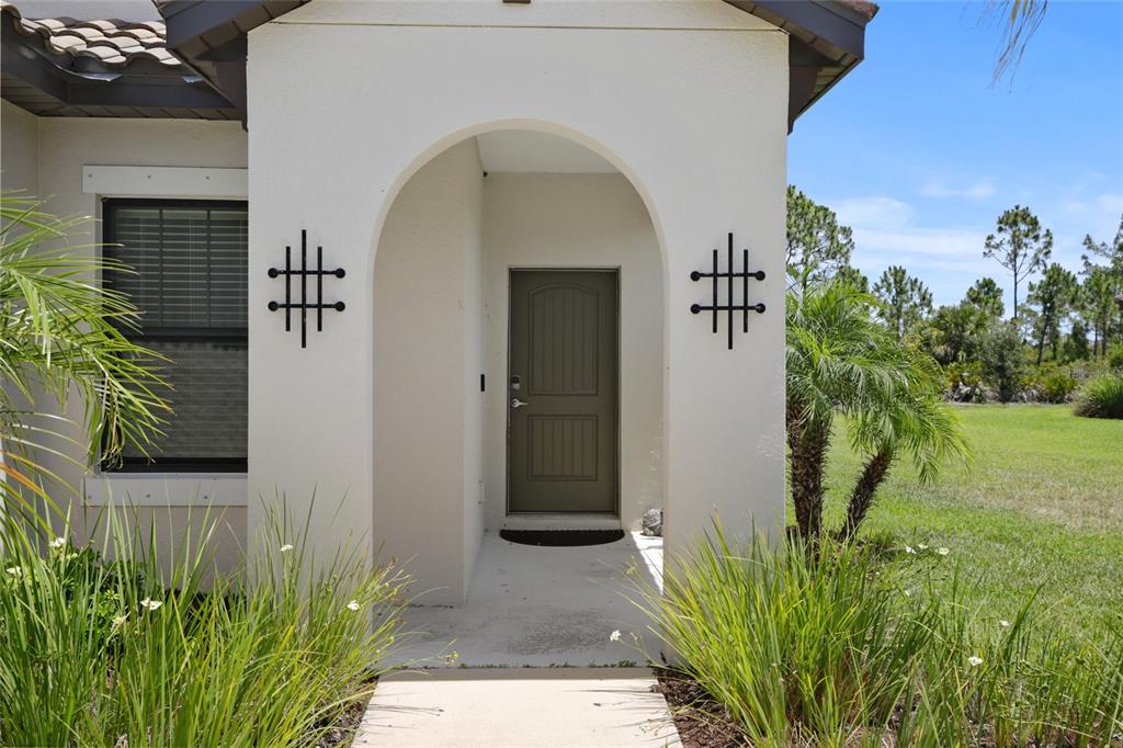 The exterior of a house features an arched entryway with decorative metal wall accents — 260 BRIENZA LOOP, NOKOMIS, FL