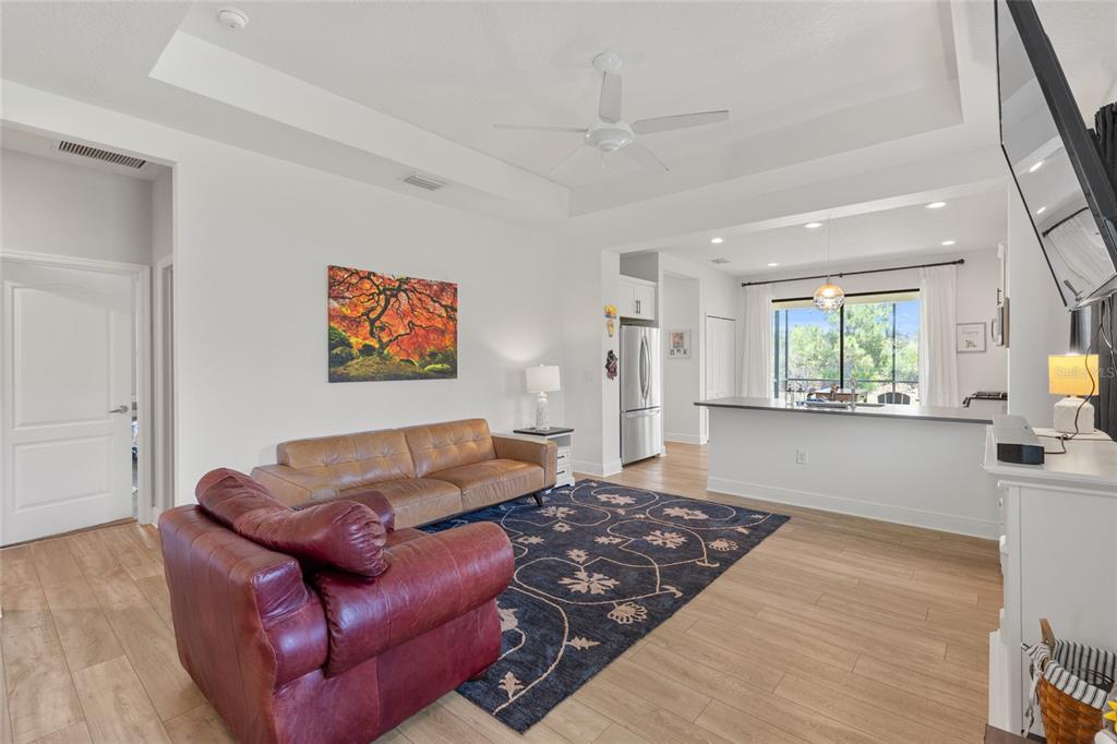 A living room with a leather sofa, red armchair, area rug, and open kitchen view — 260 BRIENZA LOOP, NOKOMIS, FL