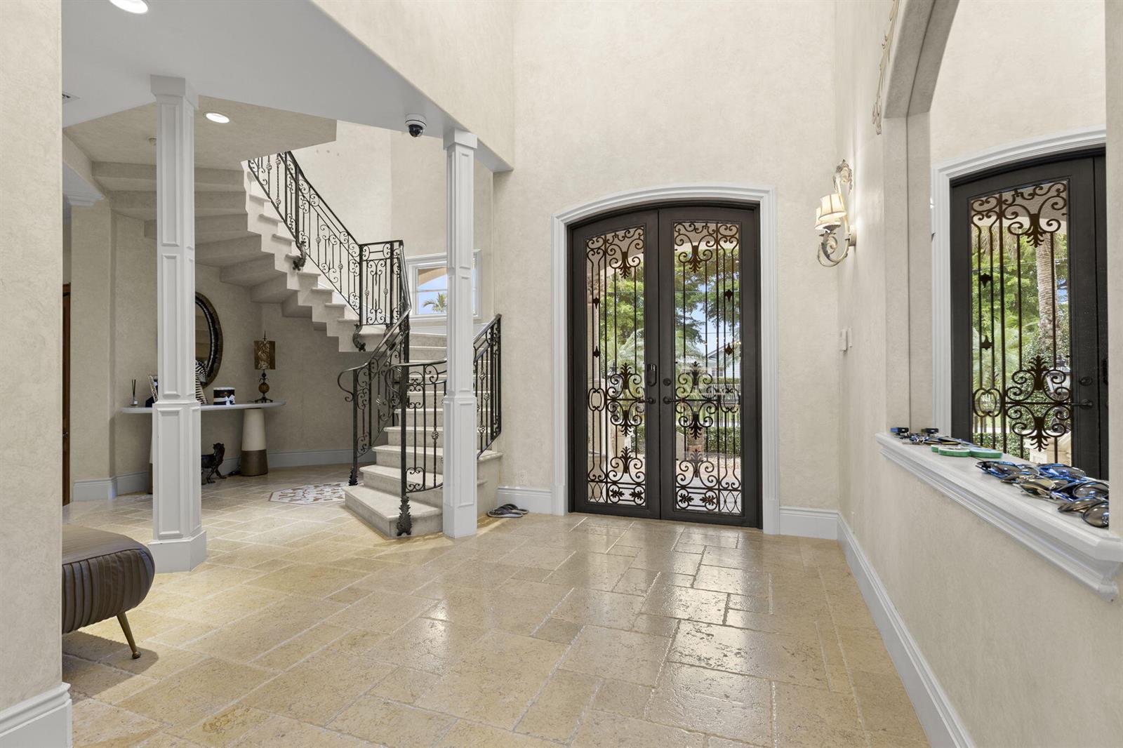 A grand foyer features a stone floor, a wrought-iron staircase, and double glass-paneled entry doors — 3131 NE 27th Avenue, Lighthouse Point FL 33064, LIGHTHOUSE POINT, FL