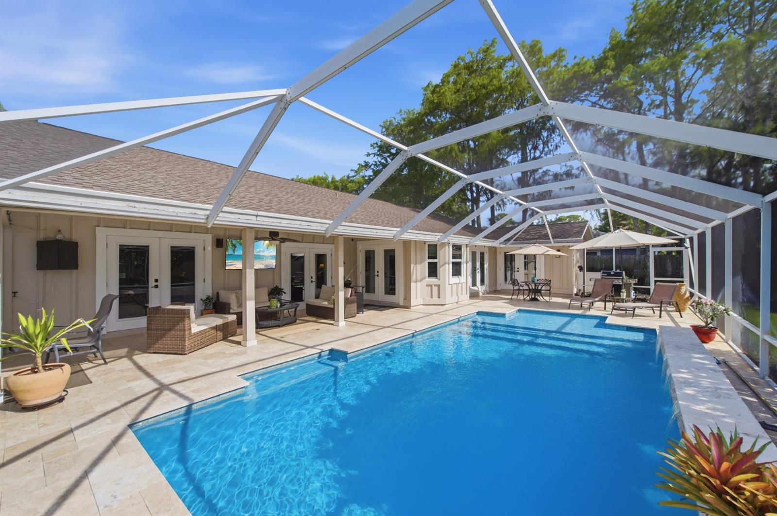 A screened-in patio features a rectangular swimming pool, beige tile decking, and outdoor furniture — 805 Daffodil Drive, Wellington FL 33414, WELLINGTON, FL