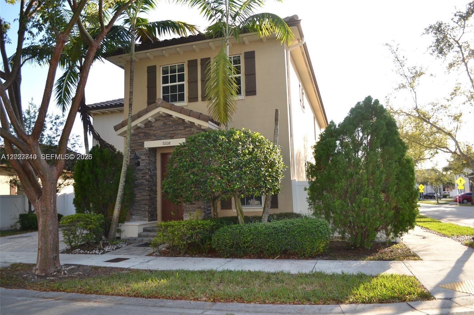A two-story house features a stone-accented entrance, brown shutters, and a palm tree out front — 9208 SW 170th Path, Miami FL 33196, MIAMI, FL