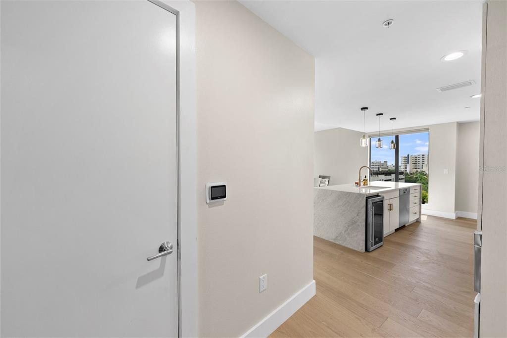 A hallway leads to a modern kitchen with a marble island and floor-to-ceiling windows — 199 DALI BOULEVARD UNIT 1001, ST PETERSBURG, FL