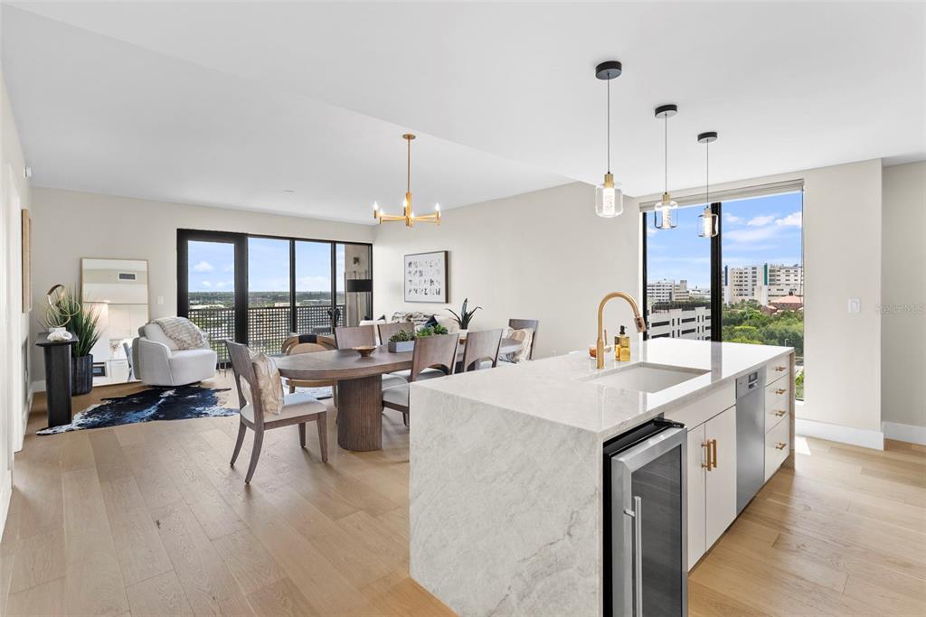 A modern kitchen island with a sink overlooks a dining area and a living space — 199 DALI BOULEVARD UNIT 1001, ST PETERSBURG, FL