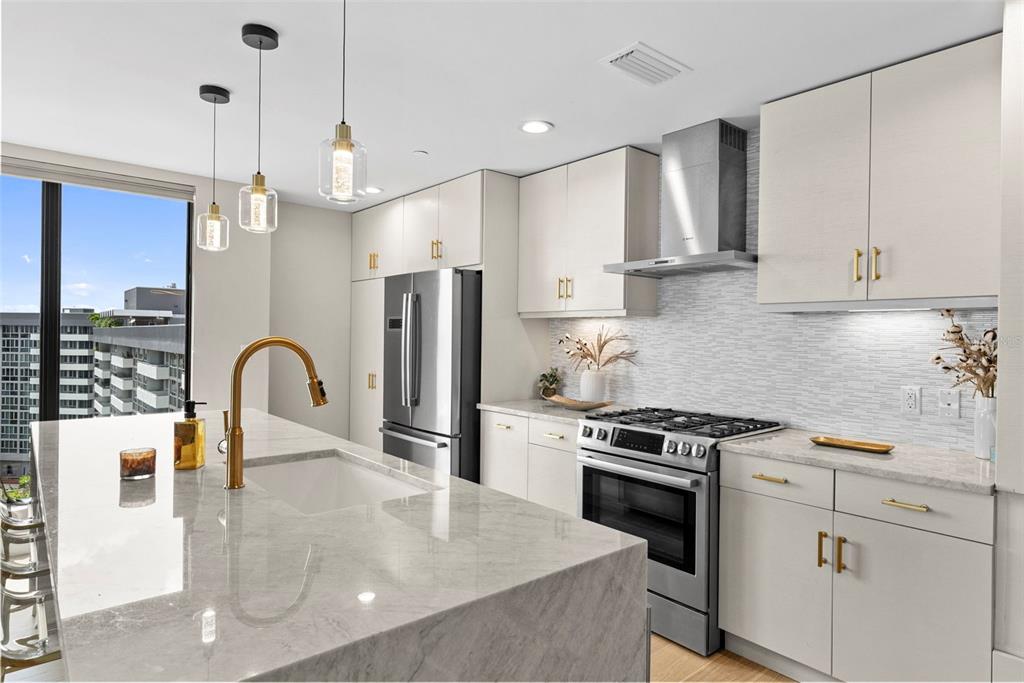 A modern kitchen features a marble island, stainless steel appliances, and light-colored cabinetry — 199 DALI BOULEVARD UNIT 1001, ST PETERSBURG, FL