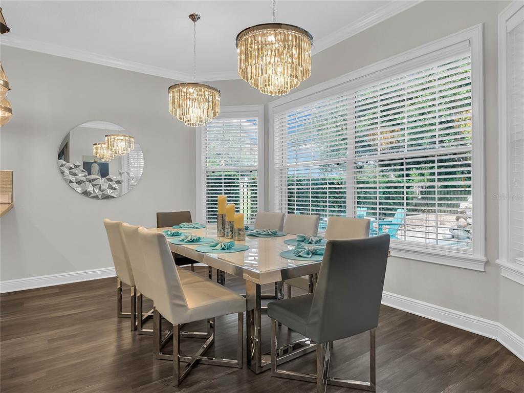 A dining room features a glass-topped table, upholstered chairs, crystal chandeliers, and large windows — 1231 RADIANT STREET, REUNION, FL