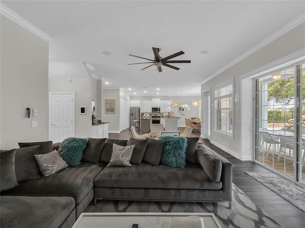 A living room with a grey sectional sofa overlooks an open-concept kitchen and dining area — 1231 RADIANT STREET, REUNION, FL
